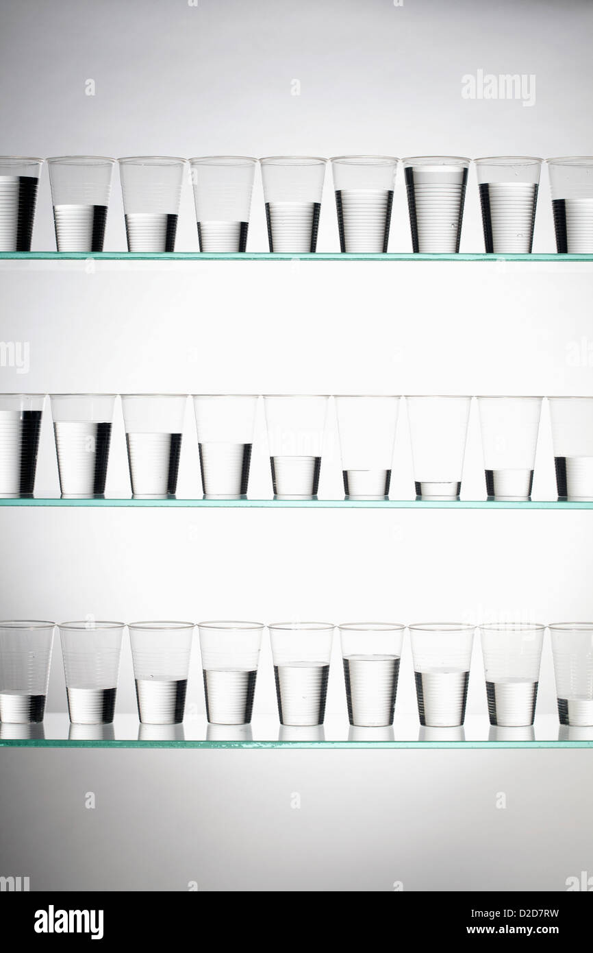 Rows of glasses filled with varying amounts of water Stock Photo