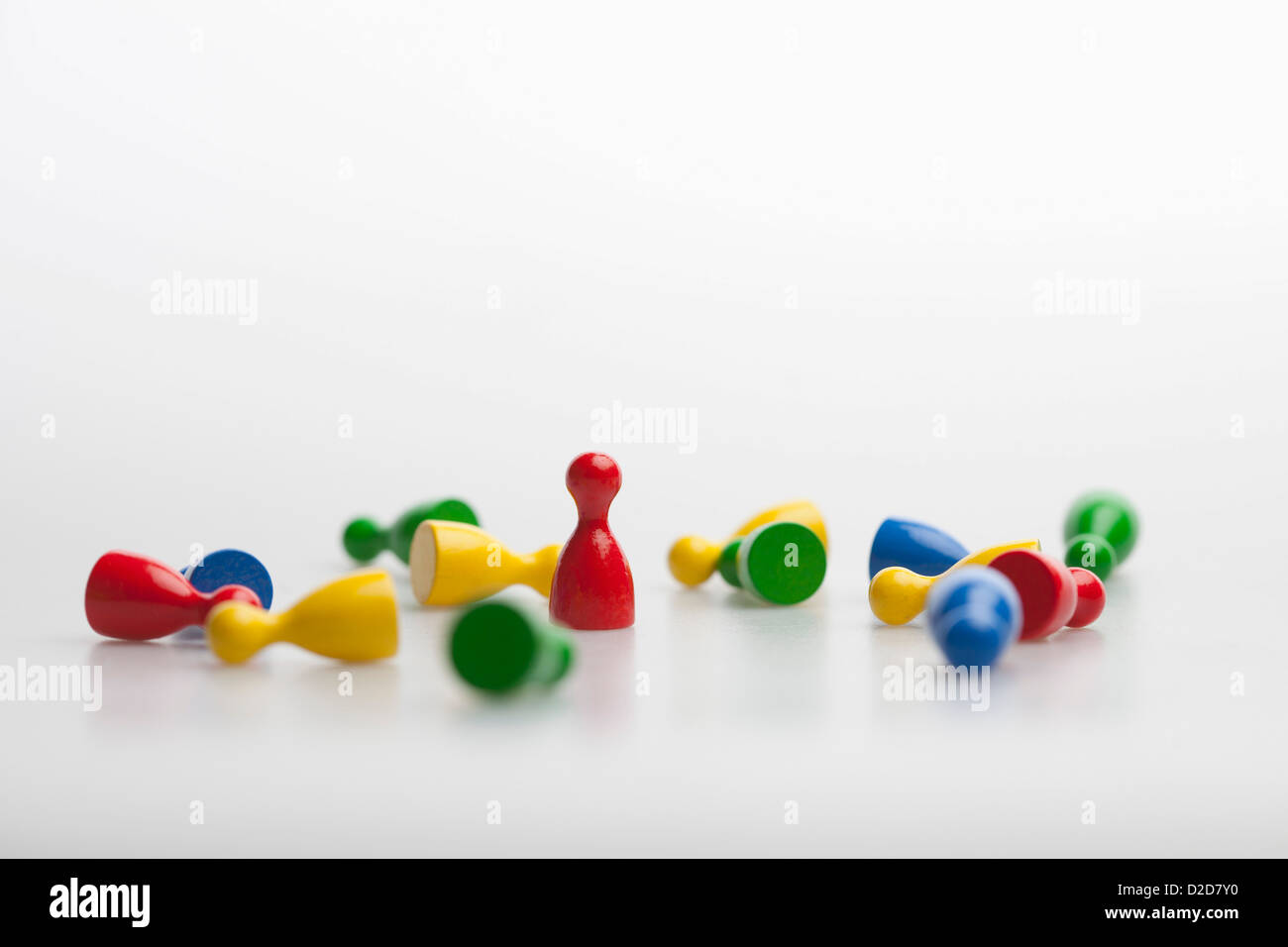 Upright game piece amongst many knocked down game pieces Stock Photo
