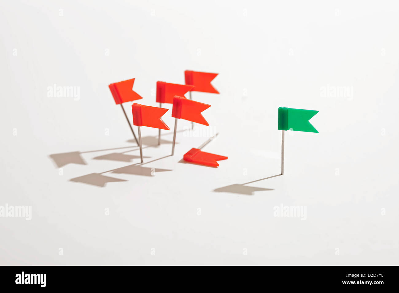Green flag standing apart from red flags Stock Photo
