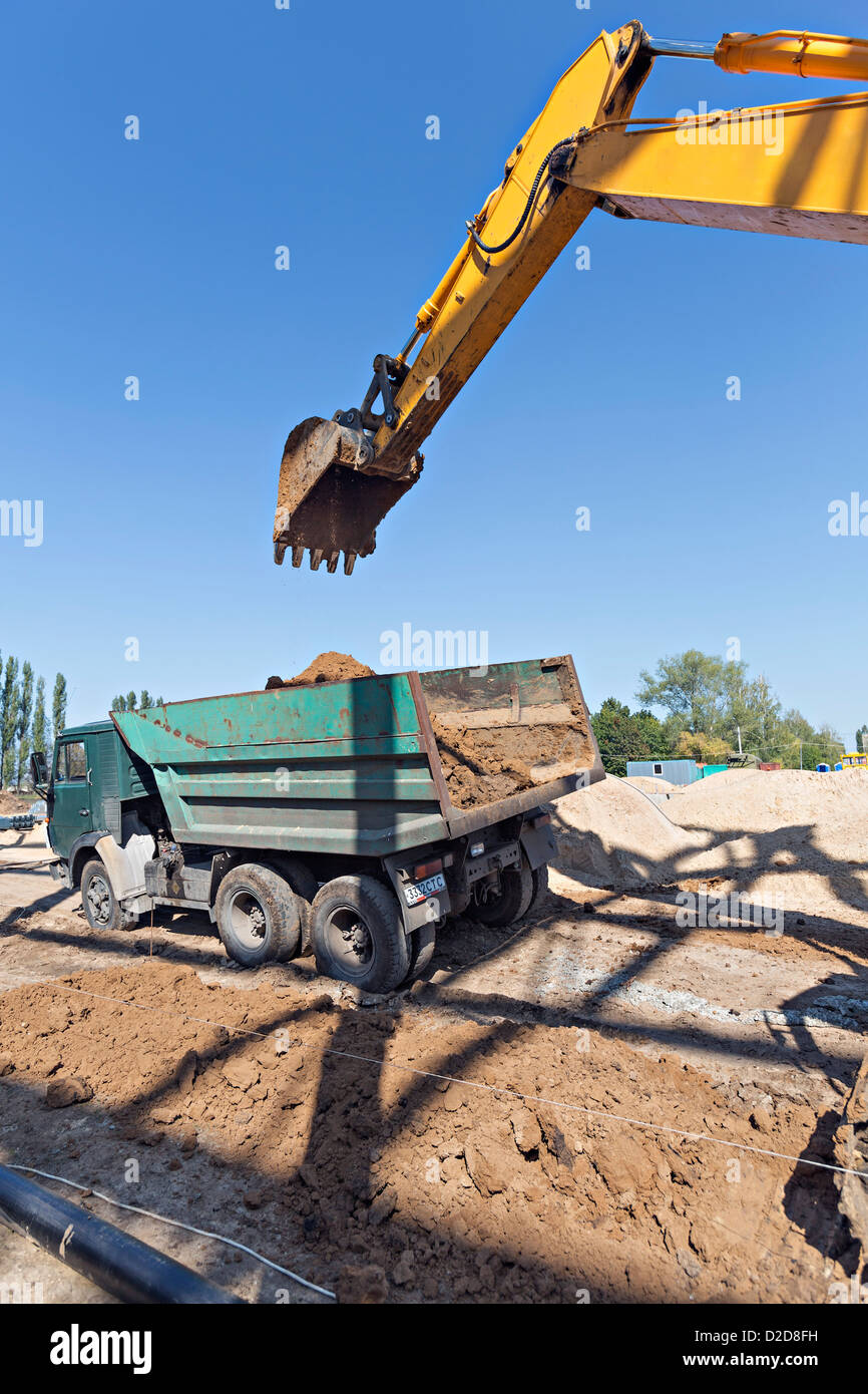 Digger loading soil onto dumper truck Stock Photo