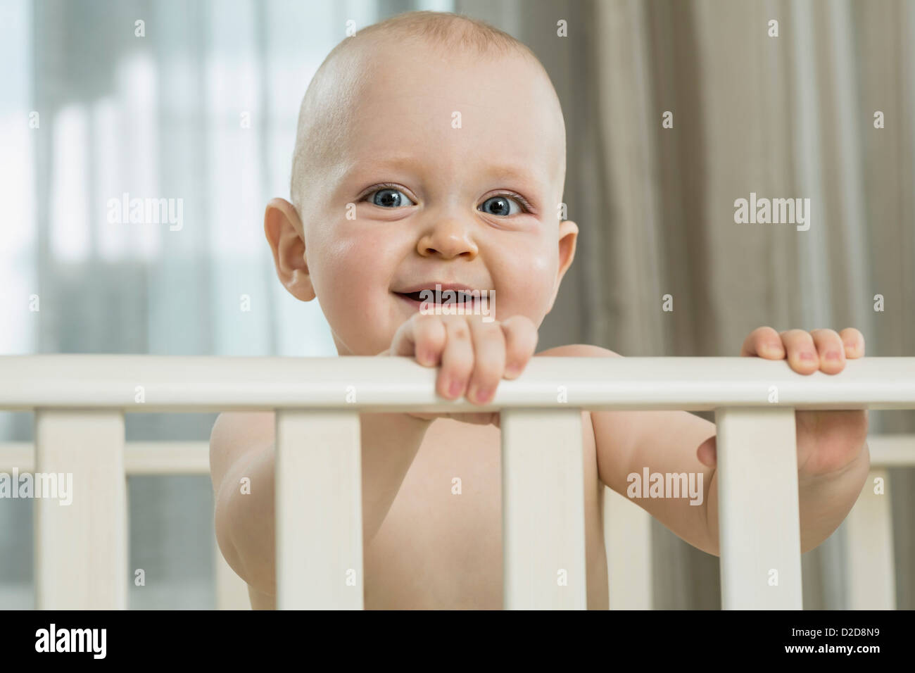 Baby standing in cot Stock Photo Alamy