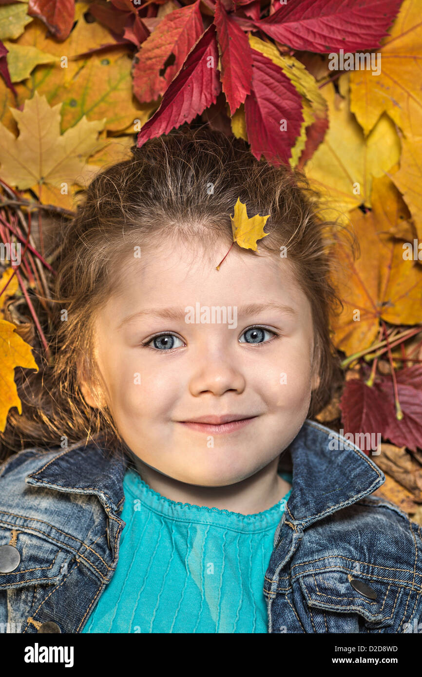 A young girl lying amongst autumn leaves Stock Photo