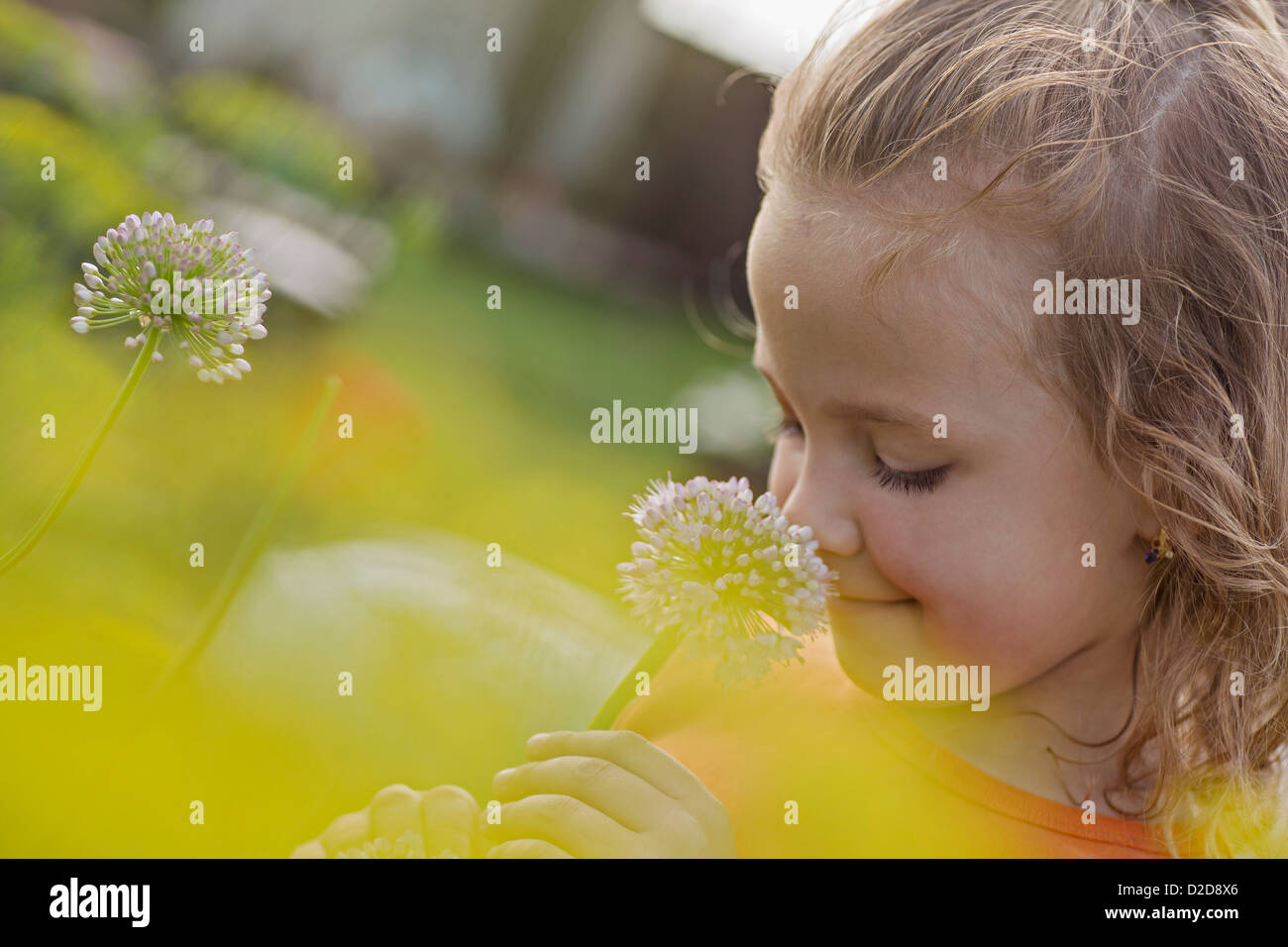 A young smiling girl smelling a flower Stock Photo