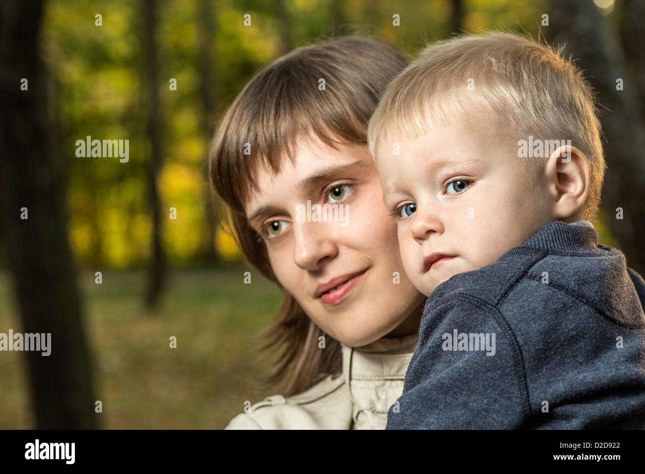 A mother holding her young son and looking away serenely Stock Photo
