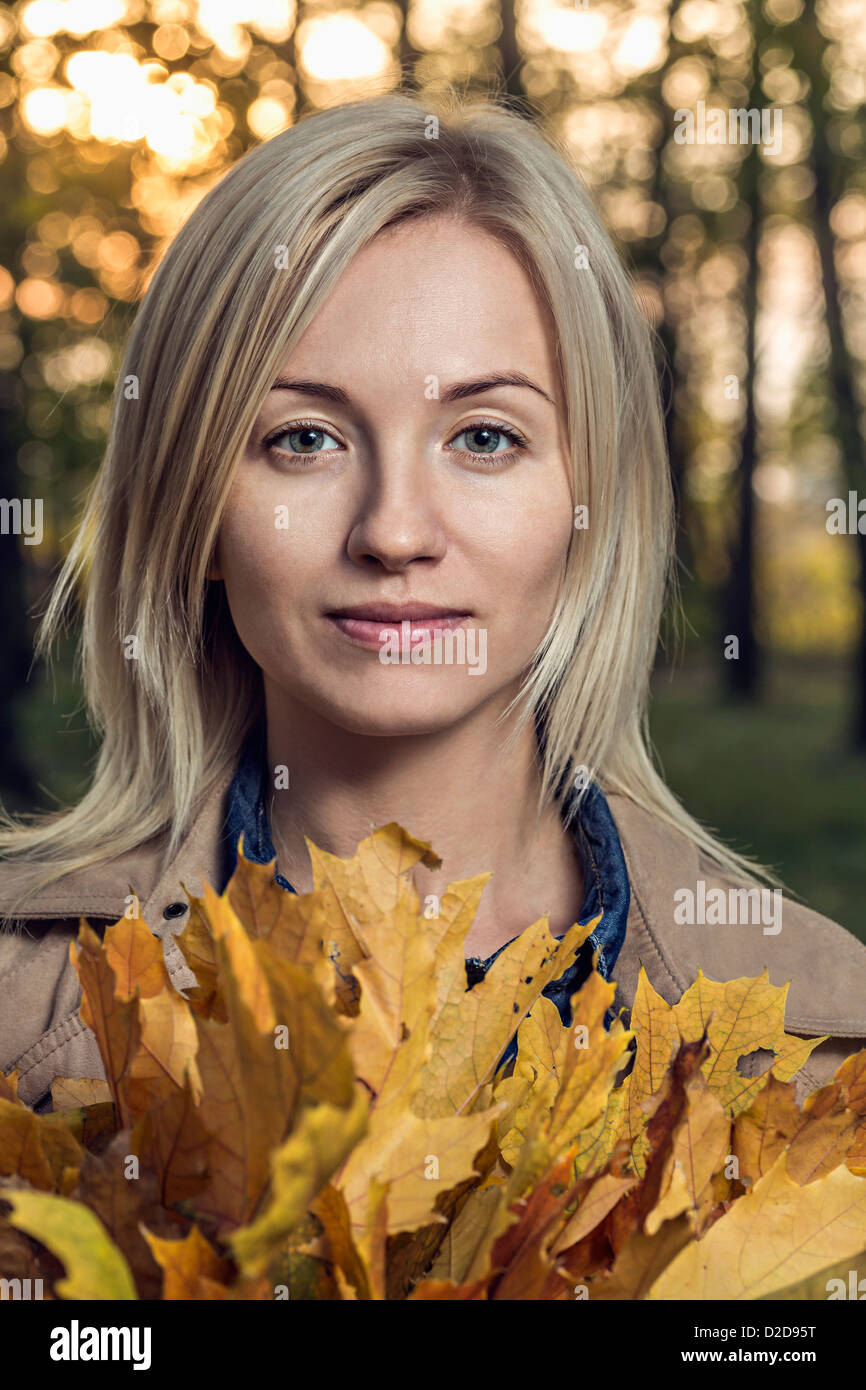 A young woman holding a bunch of autumn leaves in nature Stock Photo