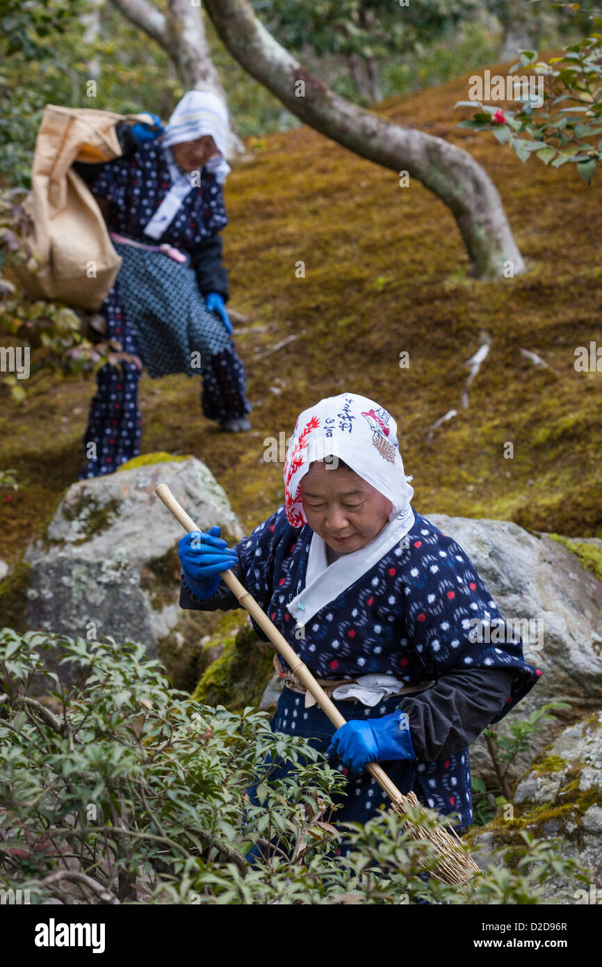 Kyoto, Japan - March 19, 2012: Two female gardeners in traditional outfits tidy the grounds at Kinkaku-ji Temple in Kyoto, Japan Stock Photo
