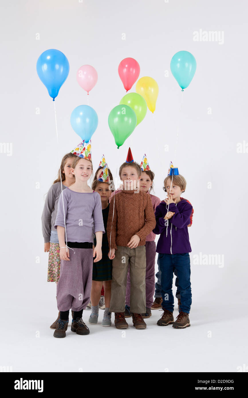 A group of kids wearing party hats and holding balloons Stock Photo - Alamy
