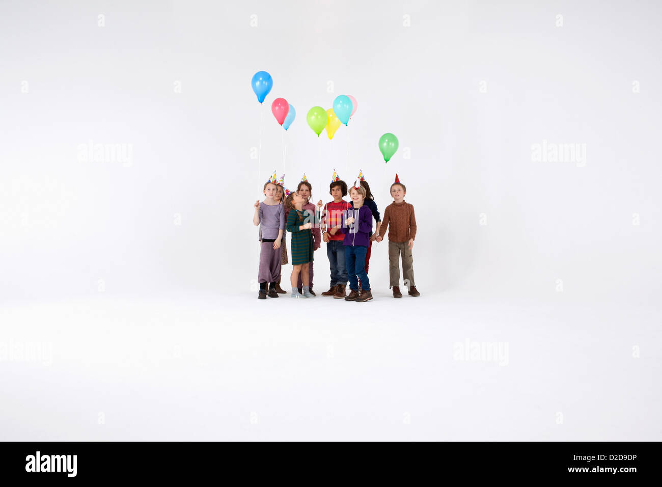 A group of kids wearing party hats and holding balloons Stock Photo - Alamy