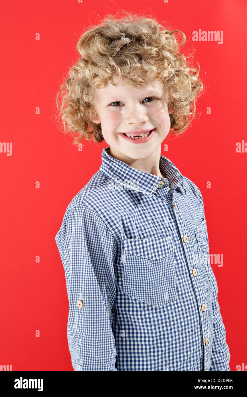 A Boy With Tousled Curly Blond Hair Smiling At The Camera Stock