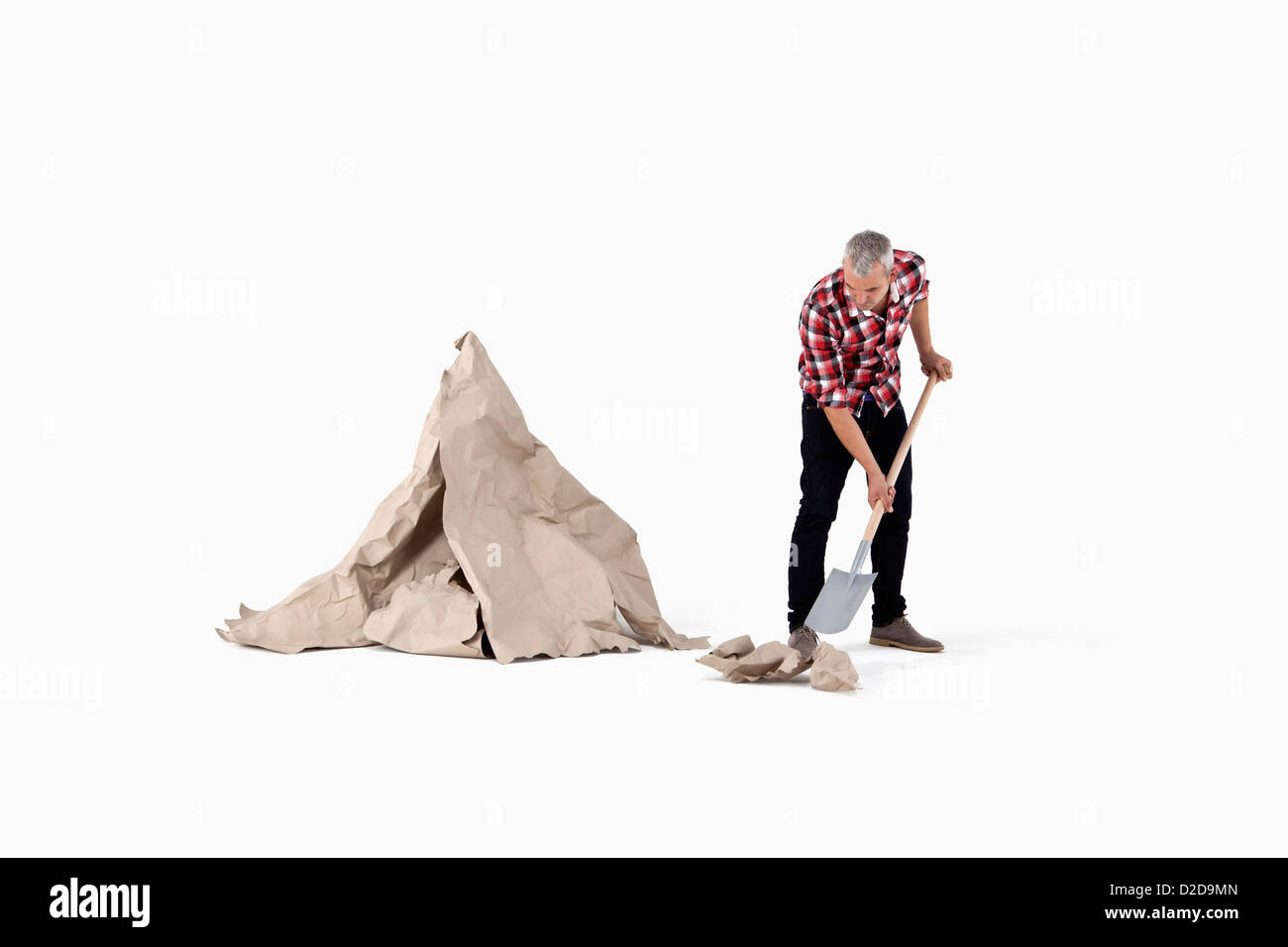 A man digging up construction paper rock, next to an artificial paper boulder Stock Photo