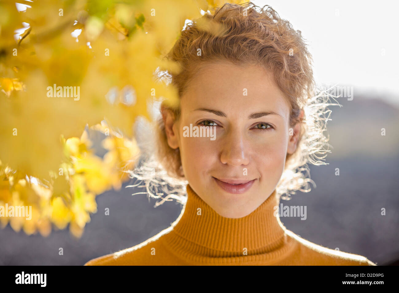 A beautiful woman standing near a tree in autumn Stock Photo