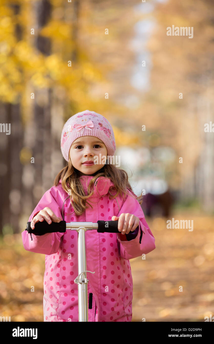 A young girl standing on a push scooter Stock Photo