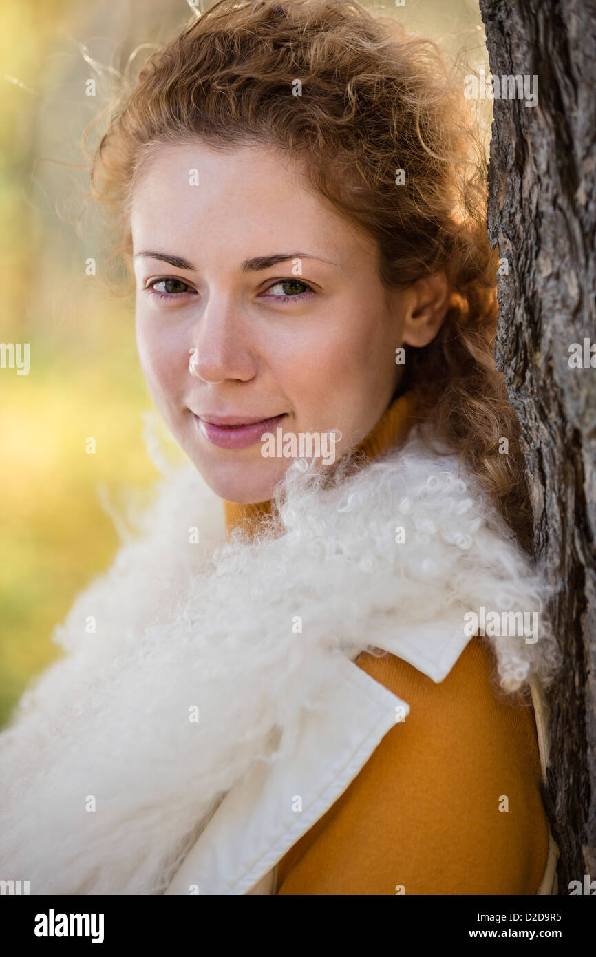 A beautiful woman leaning against a tree in autumn Stock Photo