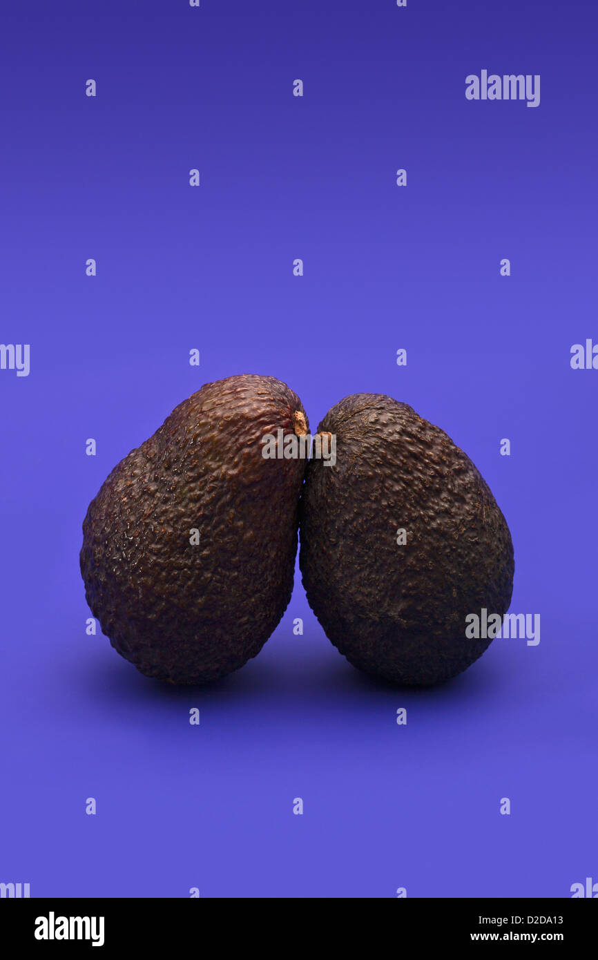 Two avocadoes leaning on each other Stock Photo