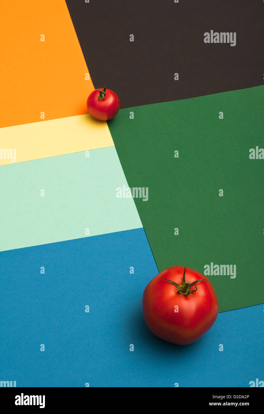 A large tomato and a small tomato placed on a multi colored geometric ...