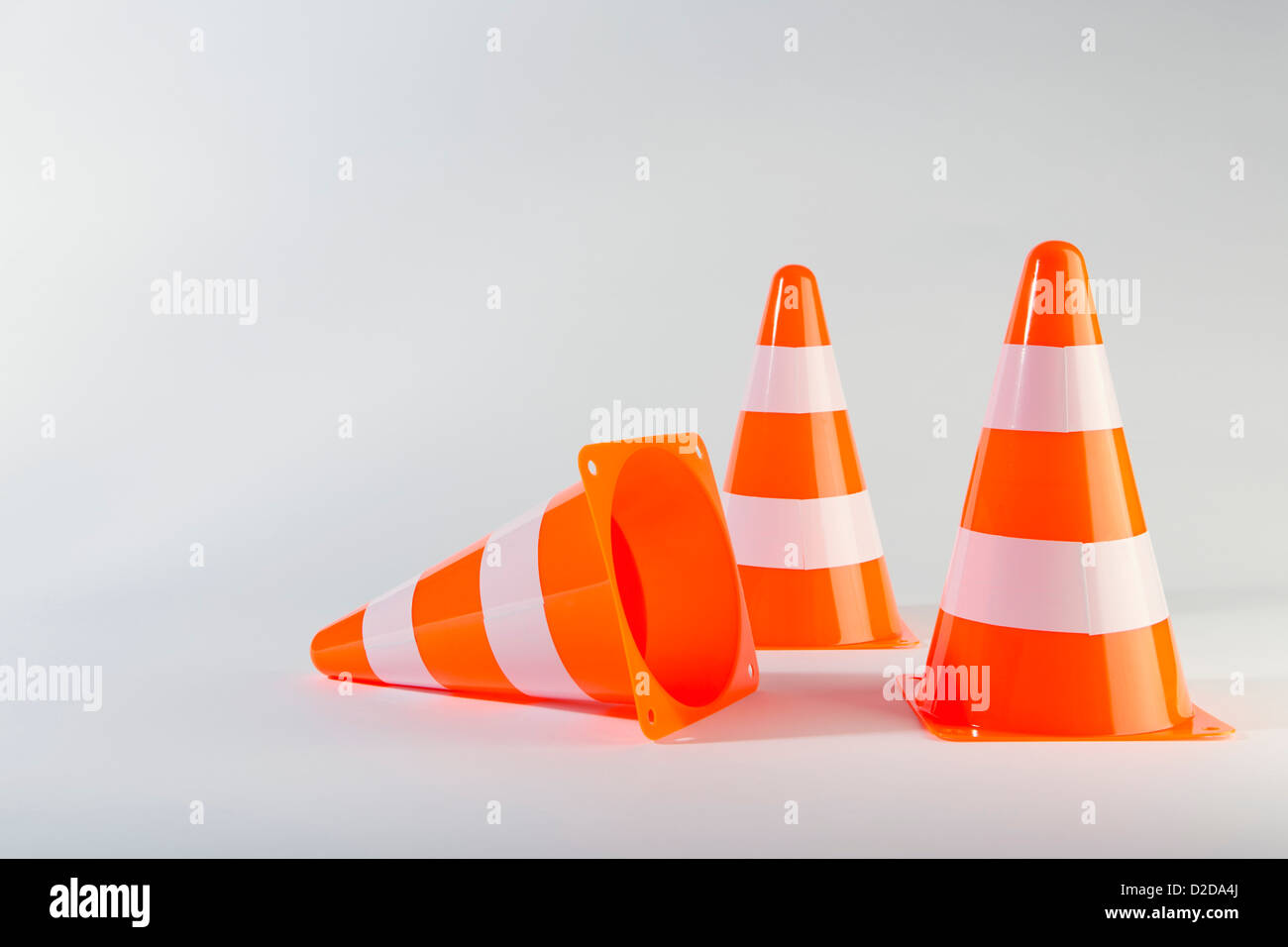 A traffic cone lying on its side next to two standing traffic cones Stock Photo