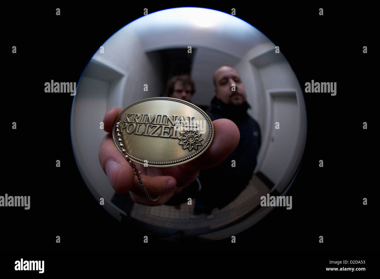 Two detectives showing a crime police (German: Kriminal Polizei) badge to a peephole Stock Photo