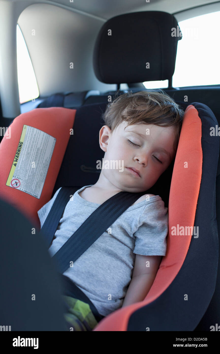 A young boy sleeping in a car seat in the back seat of a car Stock