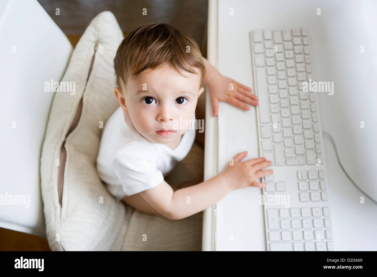 A toddler sitting at a desk with a computer keyboard Stock Photo Alamy