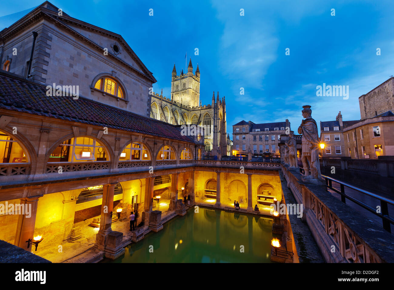 Roman Bath and Bath Abbey at night, Bath, UK. Motion blur on visitors due to long exposure. Stock Photo