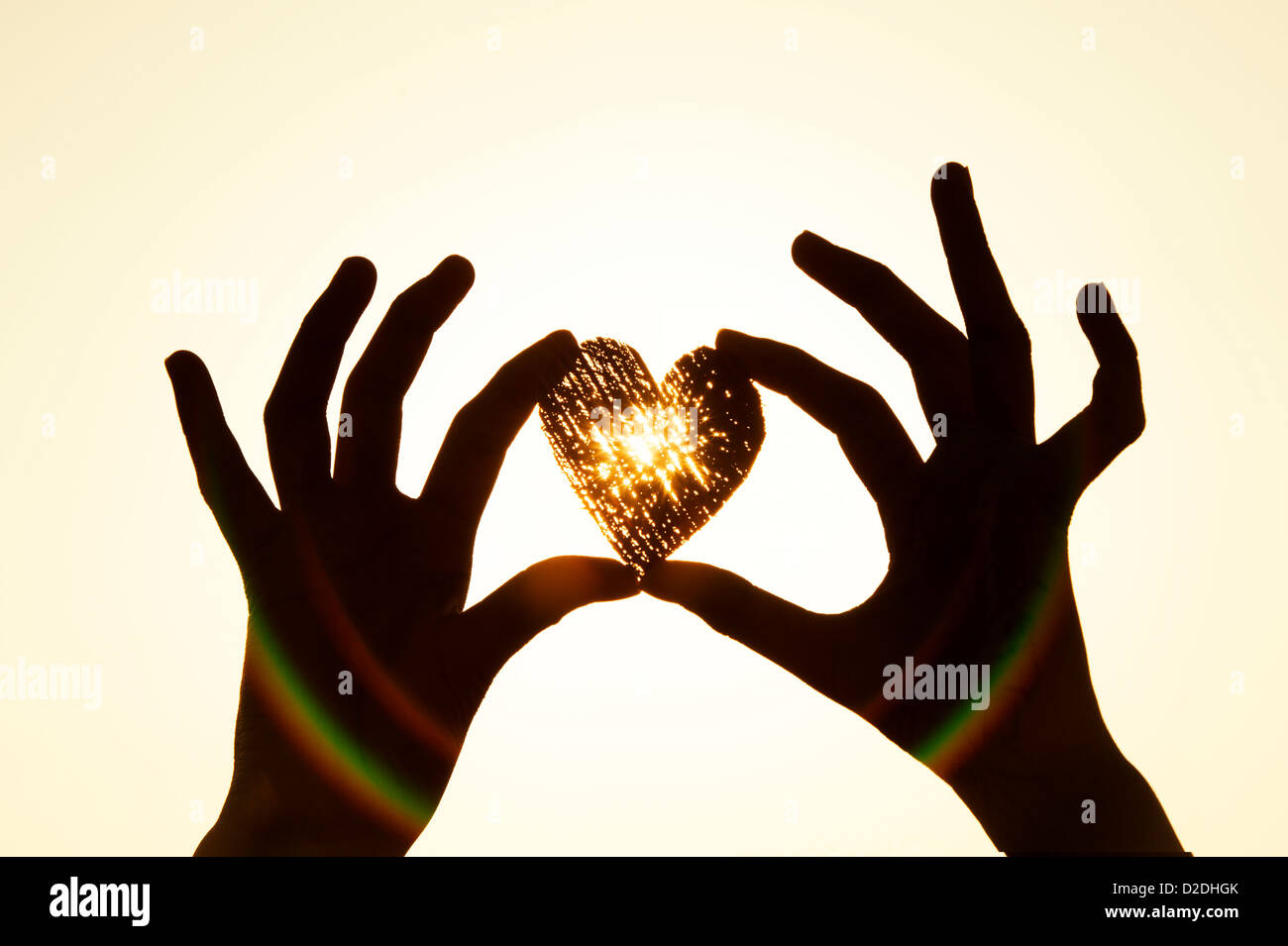 Girls hand holding heart shape at sunset. Silhouette Stock Photo