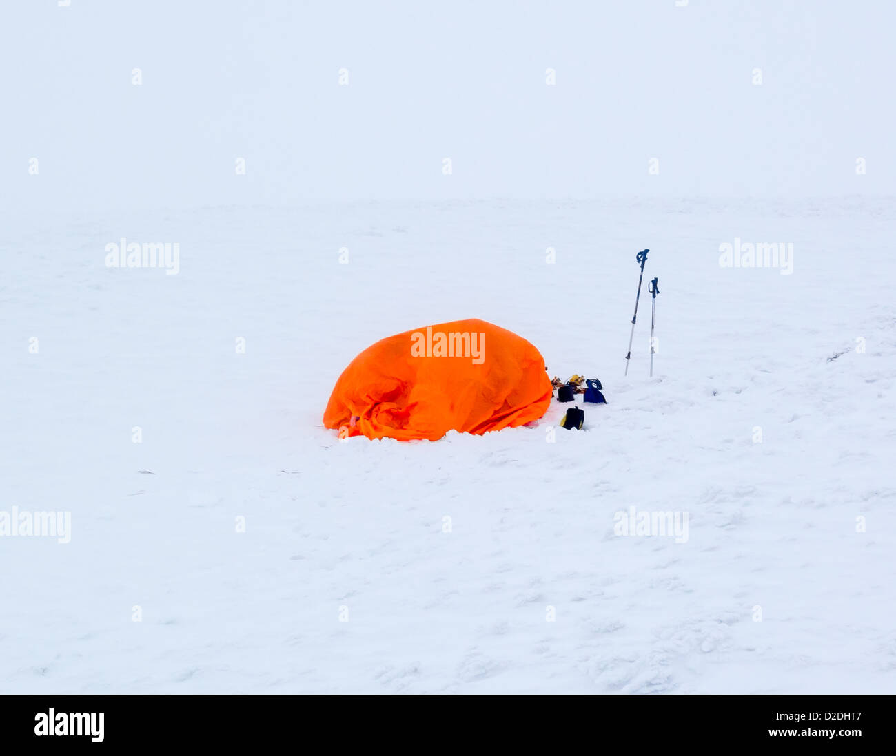 A bright orange snow survival shelter in a complete white out blizzard Stock Photo