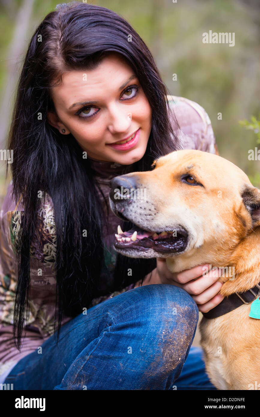 Outdoor portrait of young woman with blackmouth cur dog, Female 18 years old, long black hair, Caucasian, Texas, USA Stock Photo