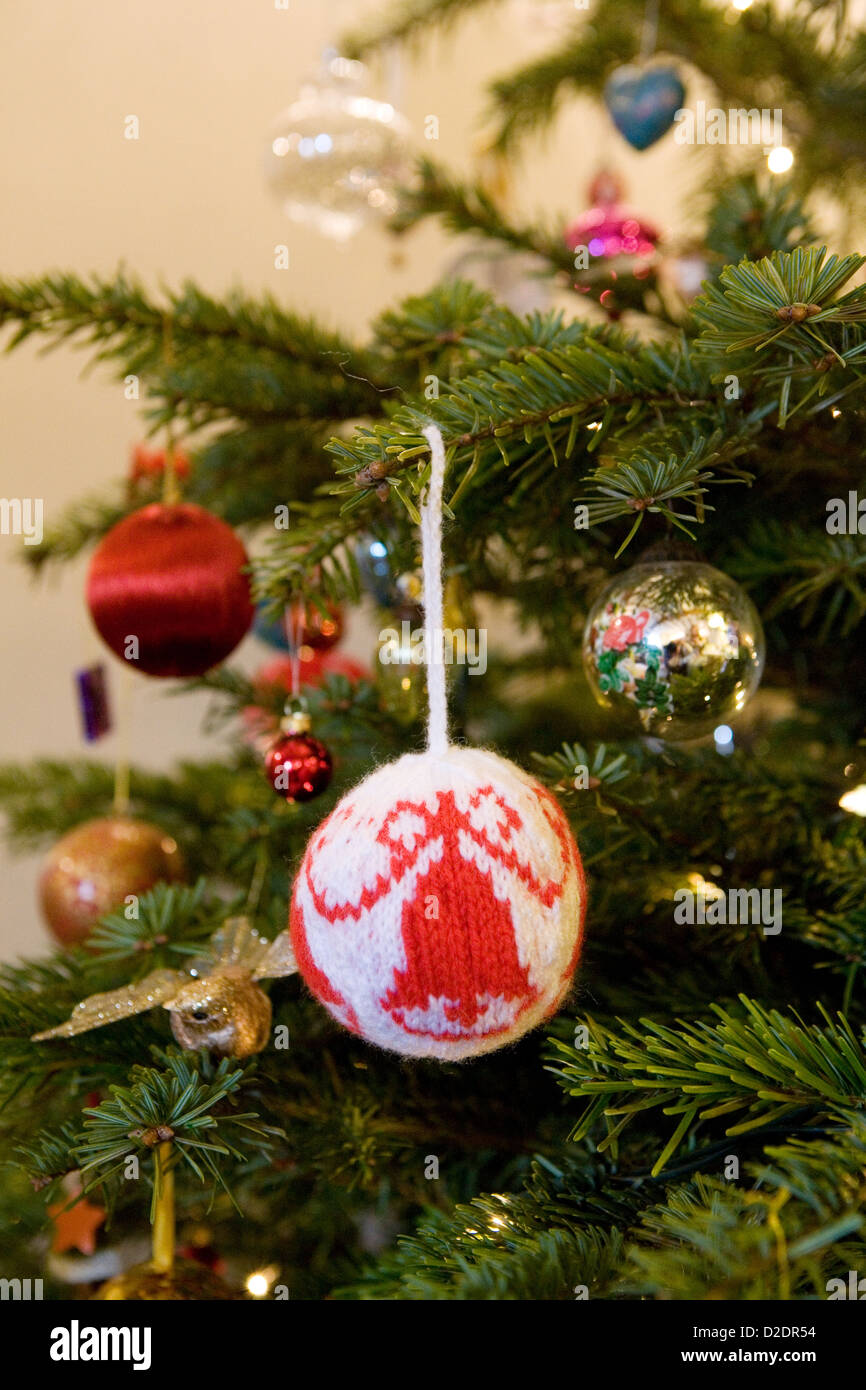 Christmas decorations hanging on a real Nordmann Fir (Abies nordmanniana) Christmas tree. Knitted and glass baubles. Stock Photo