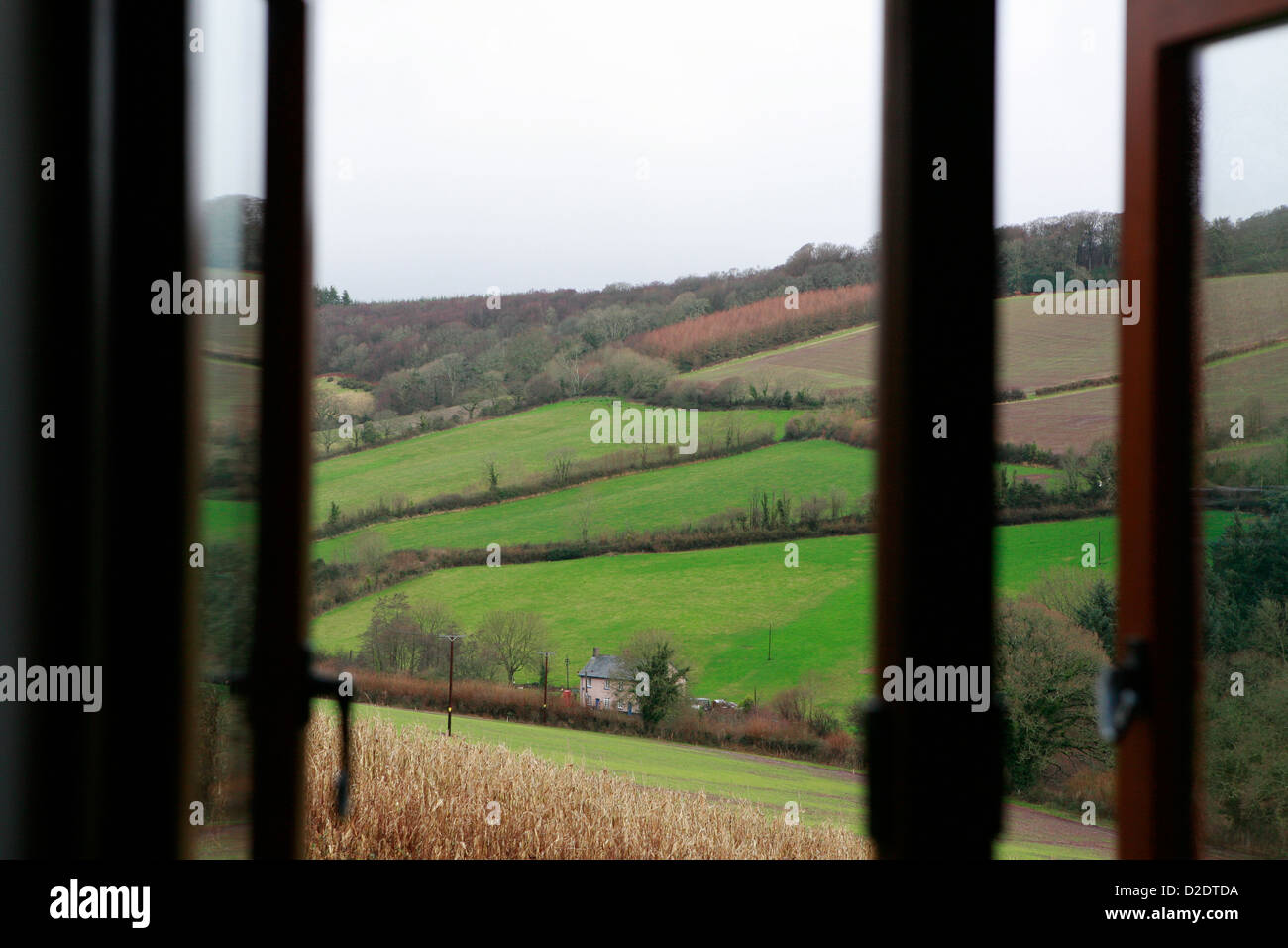 A view from an a open window of the valley countryside in Ashcombe, Devon, England. Winter landscape with only one house visible Stock Photo