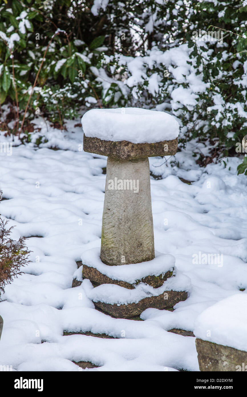 Snow covered ornamental stone bird bath in an English garden in winter Stock Photo