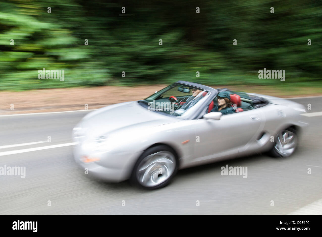 Man and woman driving an open topped MGF sports car with the roof down. Stock Photo