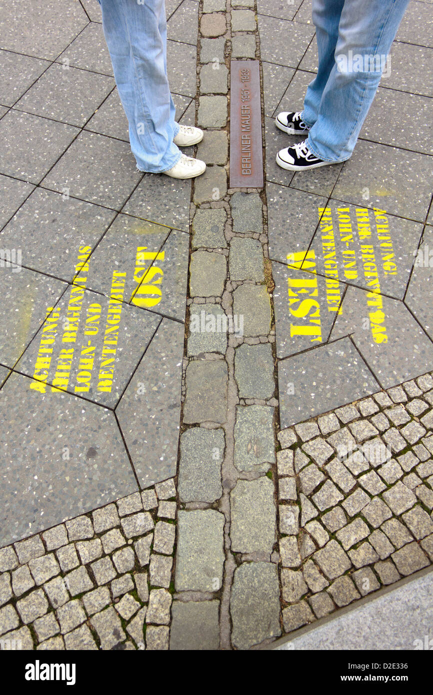 Two pairs of legs facing each other on the brought down Berlin wall in Berlin, Germany. Stock Photo