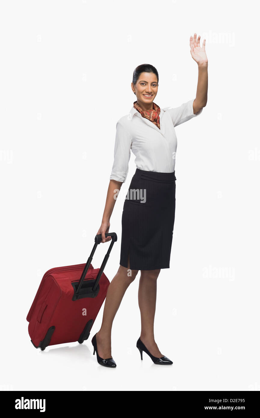 Air hostess carrying her luggage and waving Stock Photo