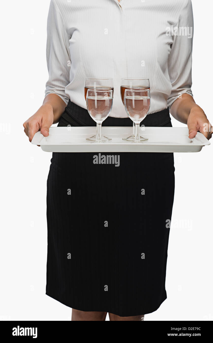 Mid section view of an air hostess carrying a tray of wine glasses Stock Photo