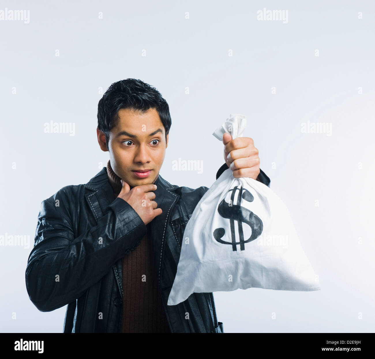 Man holding a money bag and thinking Stock Photo - Alamy
