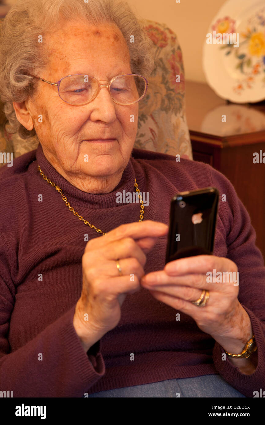 Elderly Old lady texting a message on an smart iphone Stock Photo