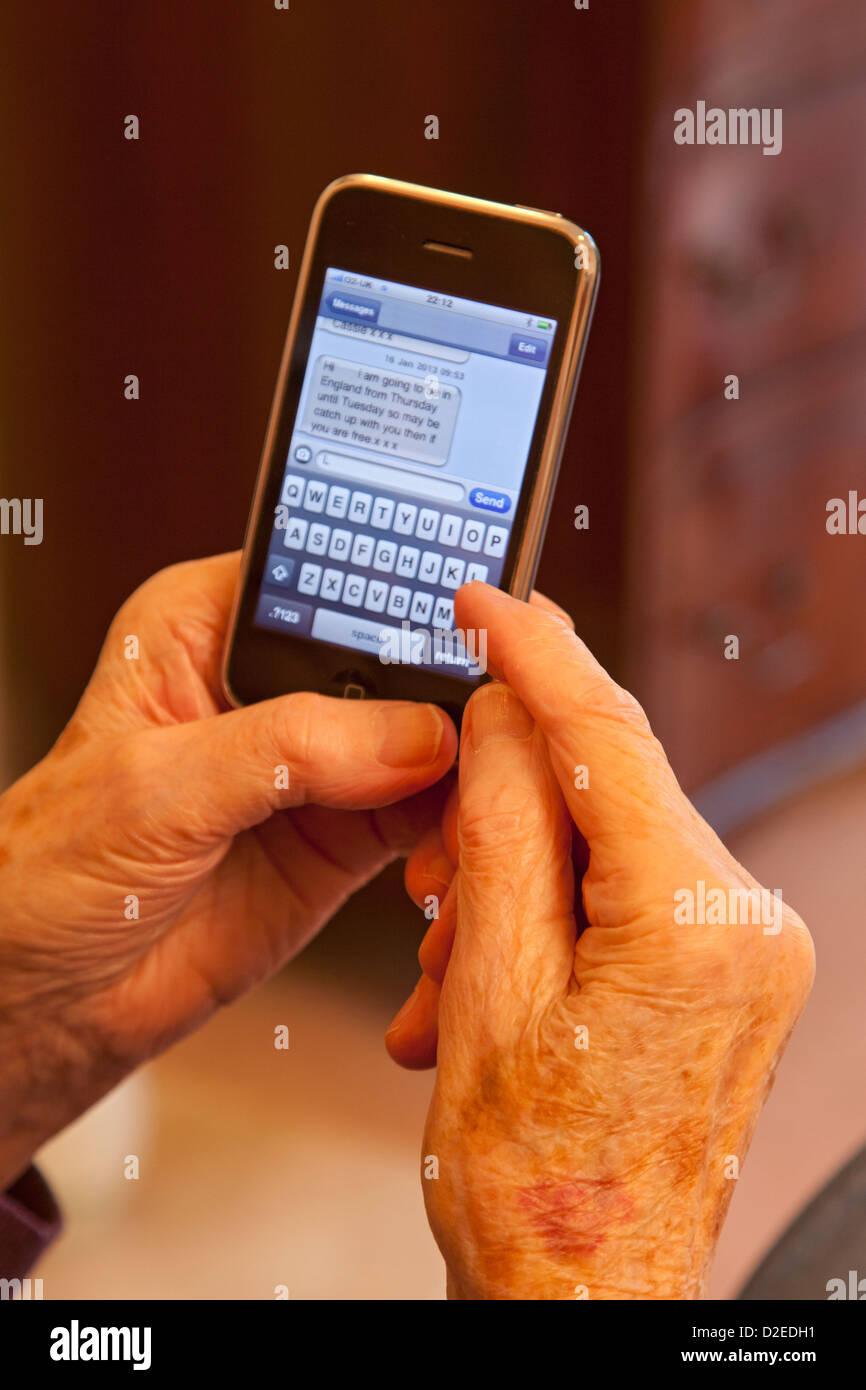 Elderly lady texting a message on an smart iphone Stock Photo