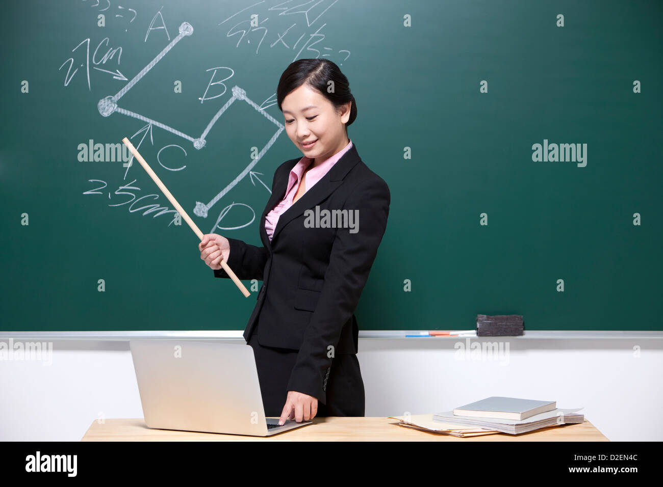 Female teacher using laptop in classroom Stock Photo - Alamy