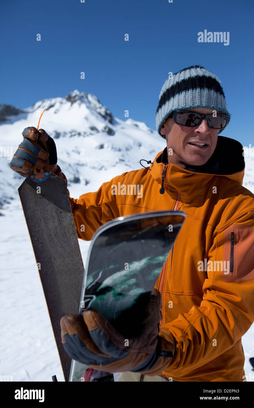 One backcountry skier putting skins on his skis and smiling. Stock Photo