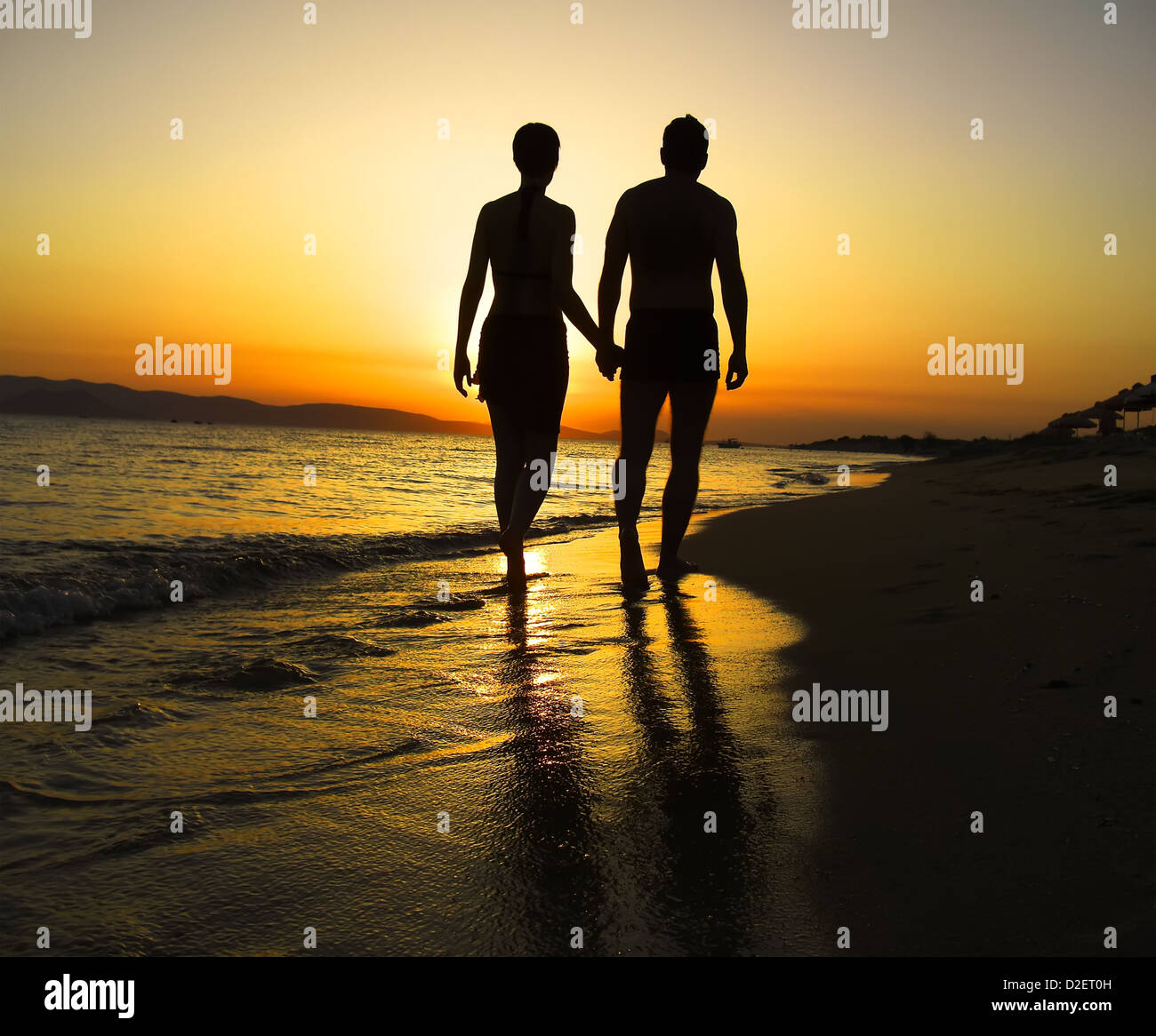 Couple walking hand in hand along beach at sunset hi-res stock ...