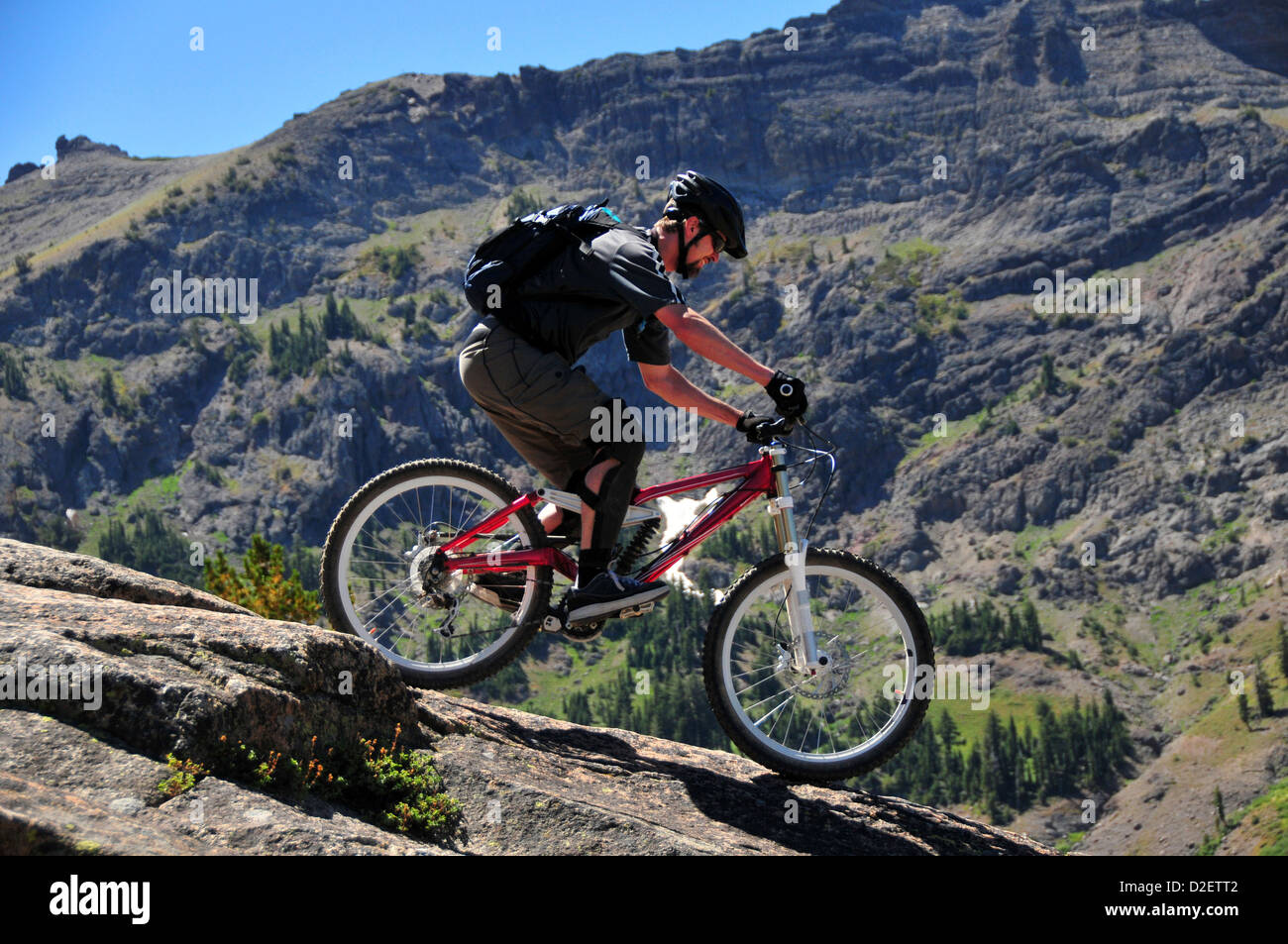 A mountain biker rides down a technical section of rock at Kirkwood Mountain Resort in the summer, CA. Stock Photo