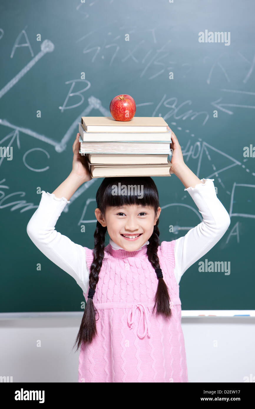 Happy little girl with textbooks and apple in classroom Stock Photo - Alamy