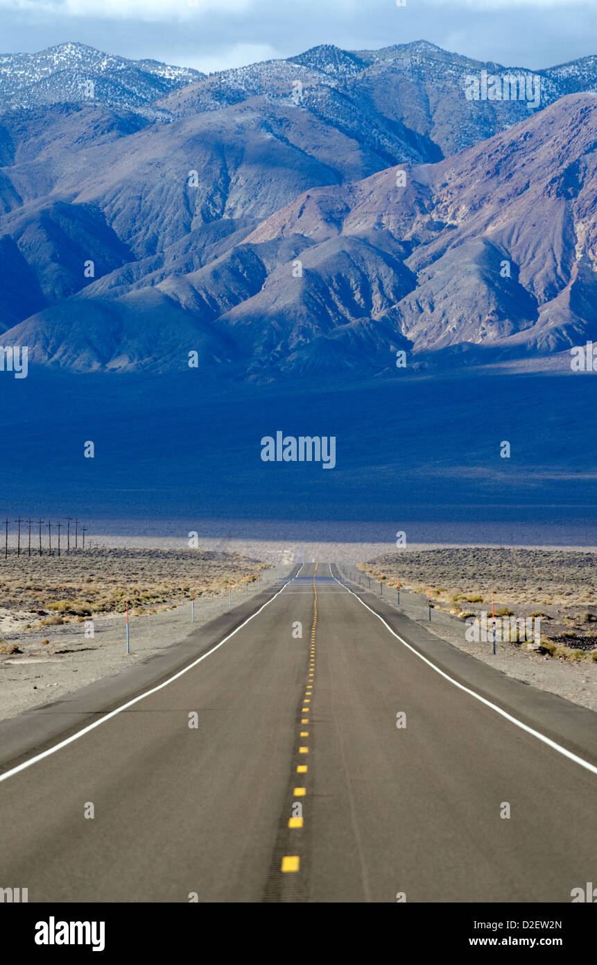 A road, Highway 95, stretches across the desert with mountains in the distance near Hawthorne, NV. Stock Photo