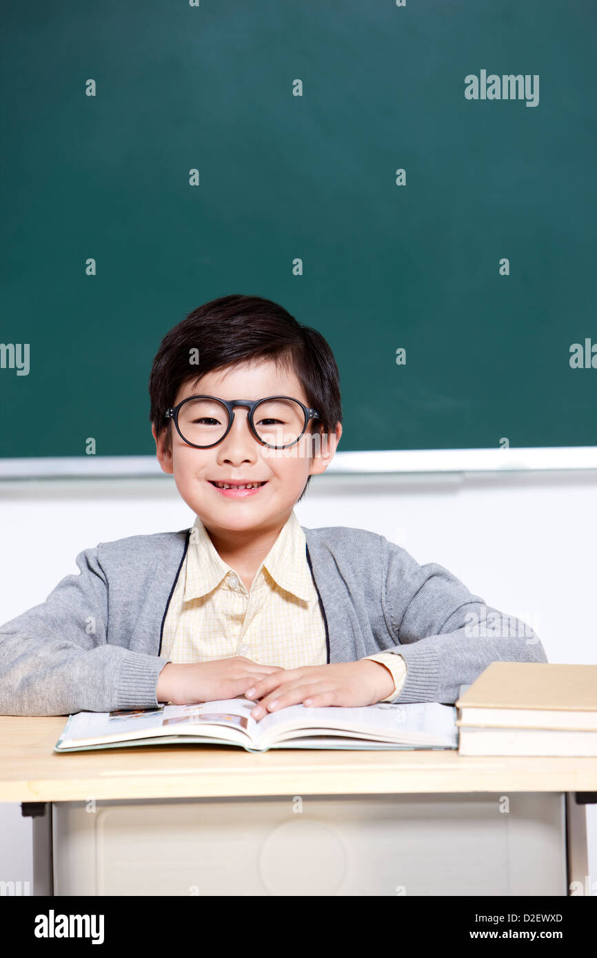 Lovely schoolboy reading a book in classroom Stock Photo - Alamy