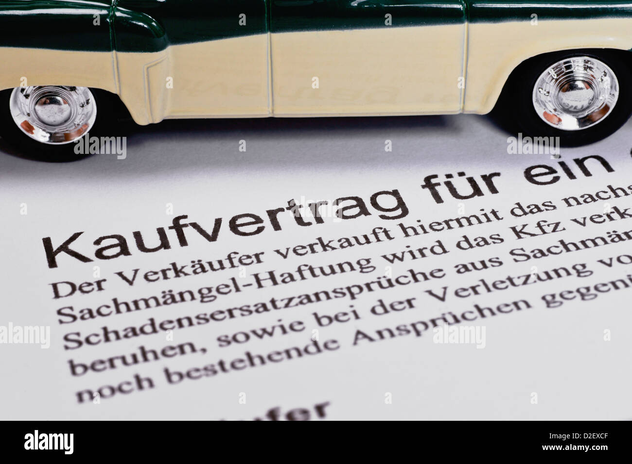 Detail photo of a Car sales agreement in German, alongside is a model car Stock Photo
