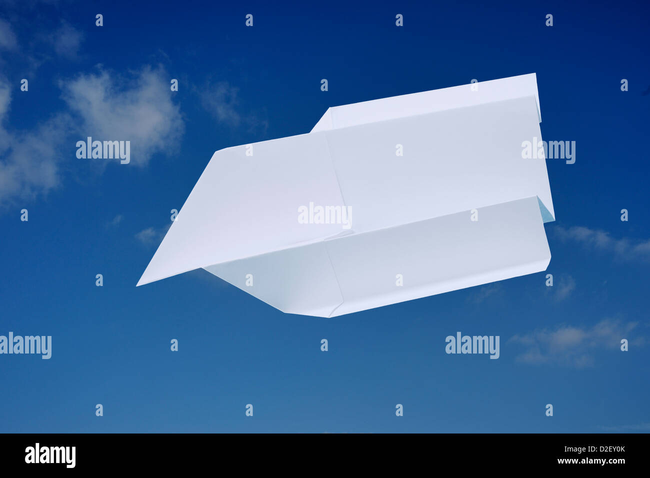ein Papierflugzeug vor blauem Himmel | a paper plane in front of blue sky Stock Photo