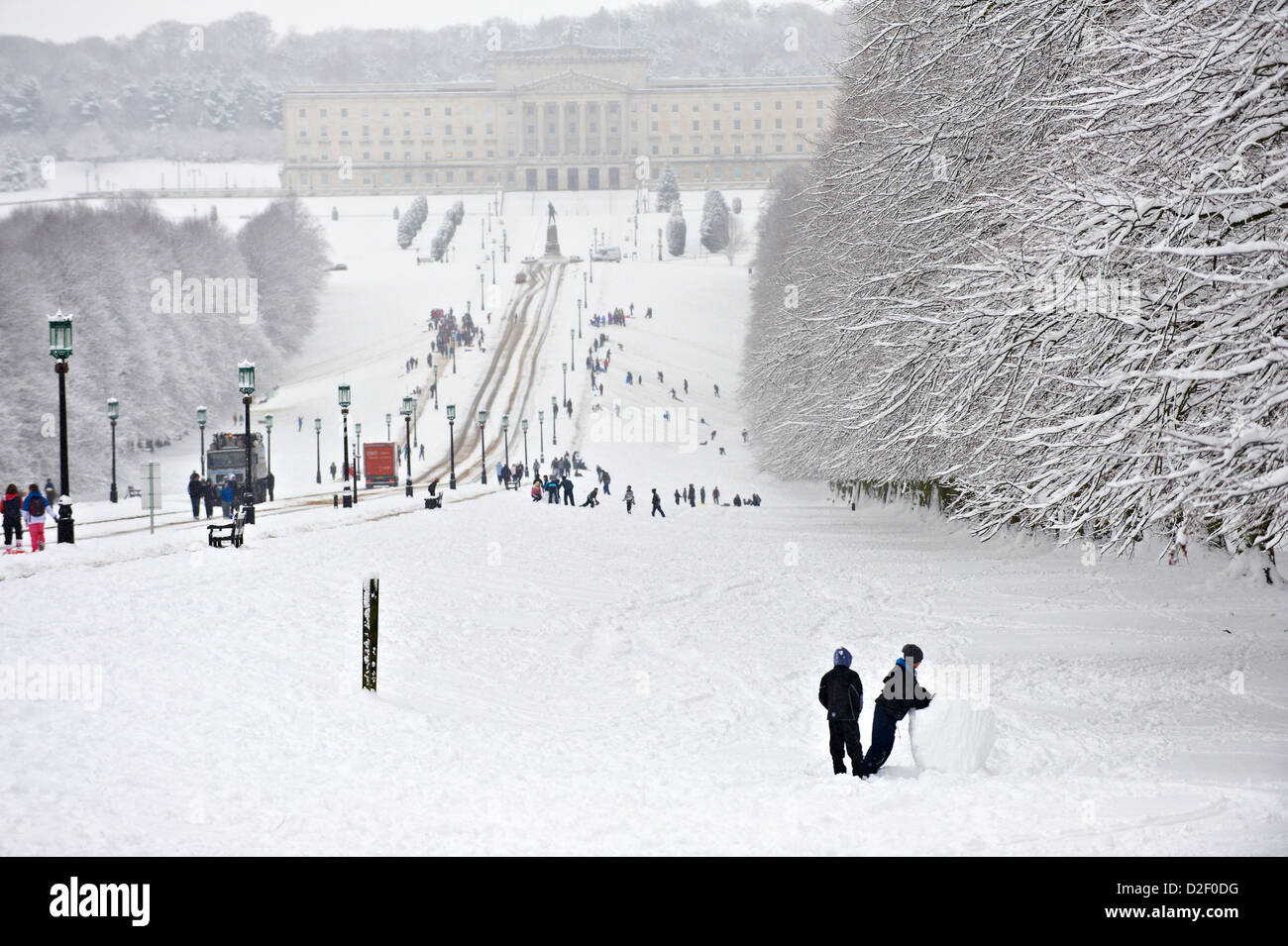 Families playing on snow in the grounds on Stormont Estate Stock Photo