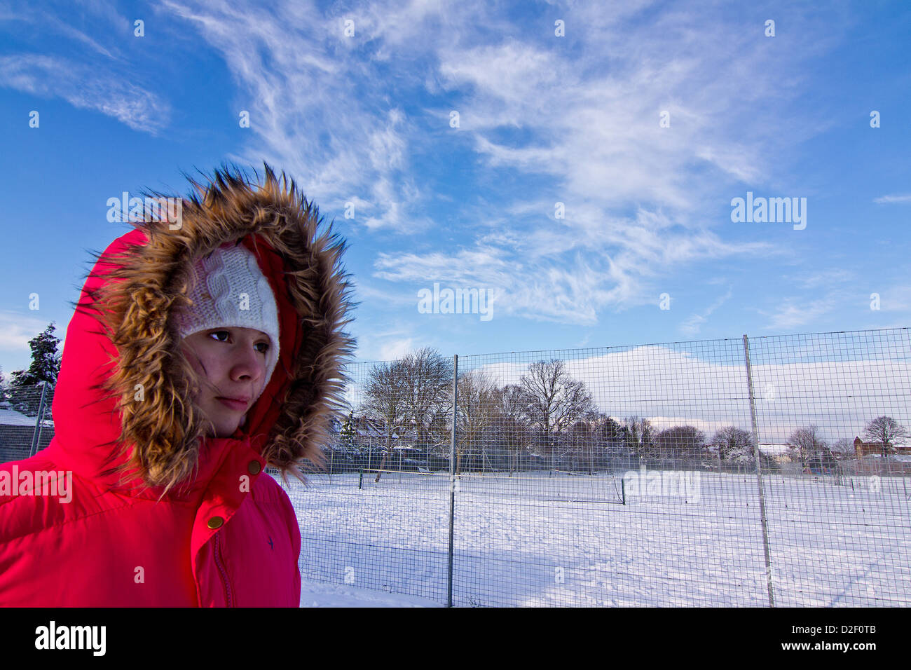 A teenage girl walks through a snow covered park in Croydon Surrey United Kingdom Stock Photo