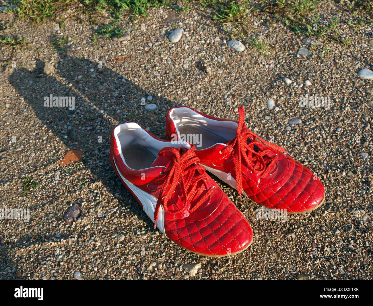 Red light leather imitation summer shoes on beach grovel, evening