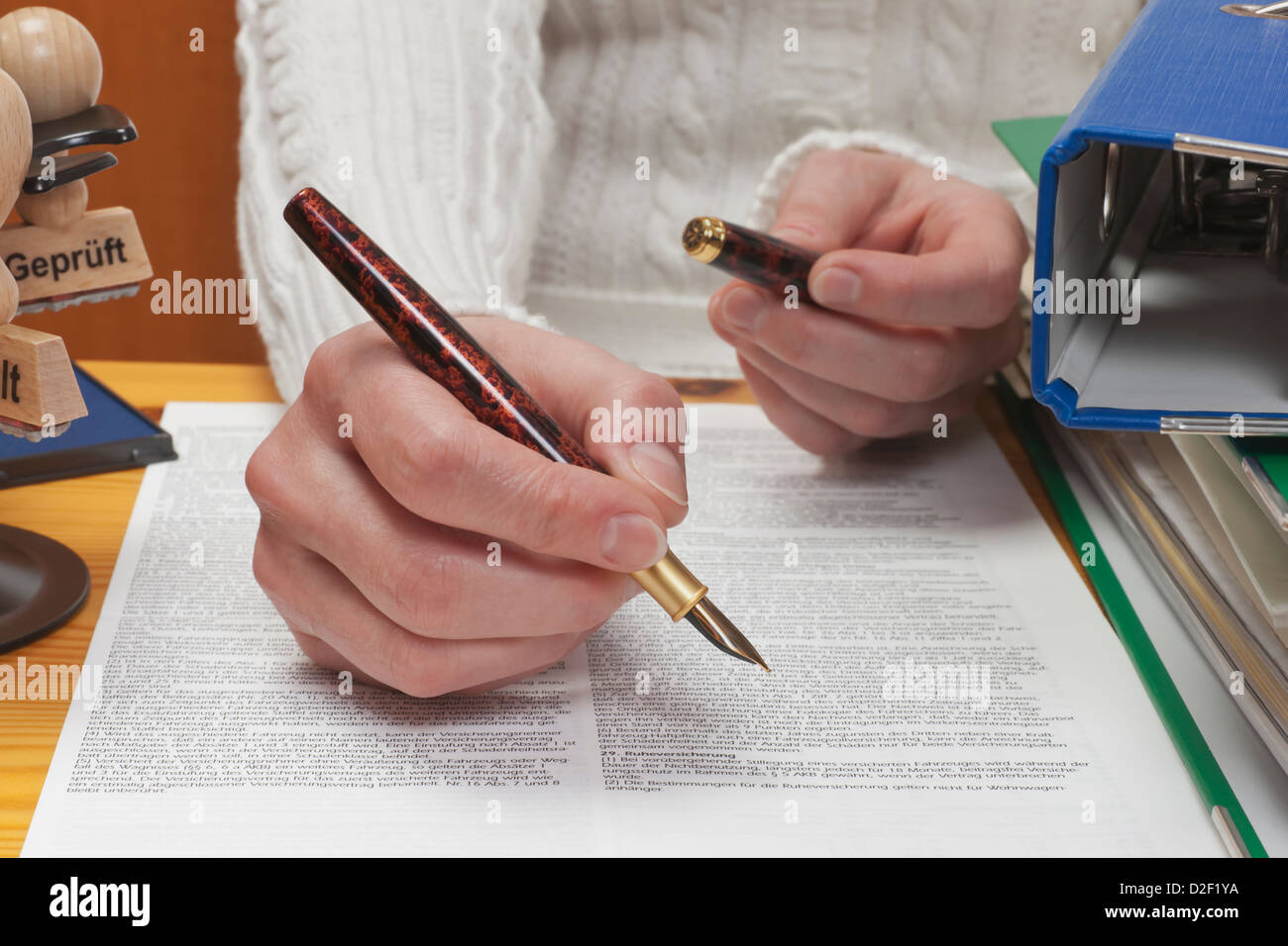 a woman sitting at desk with a pen in hand Stock Photo